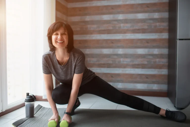 Fit mature woman exercising with dumbbells at home