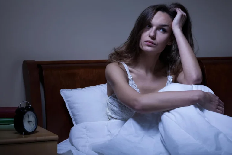 Woman sitting awake in bed at night
