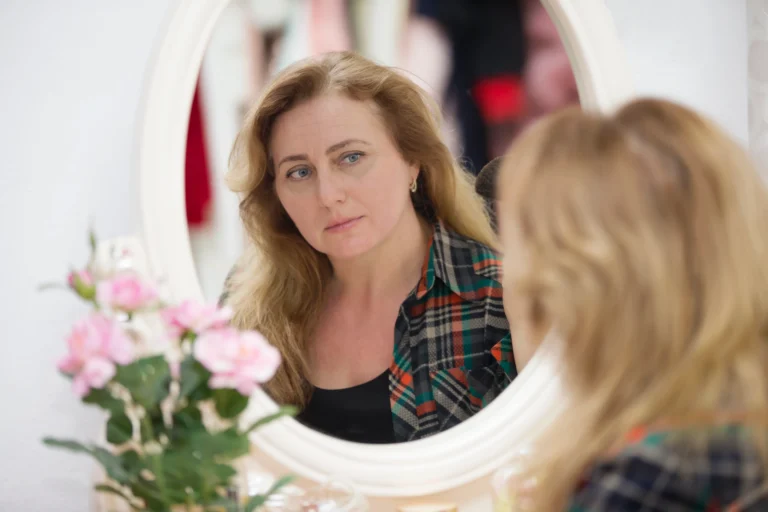 Woman looking thoughtfully at her reflection