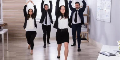 Employees participating in a workplace stretching session in a modern office, part of a corporate wellness program in Newport Beach