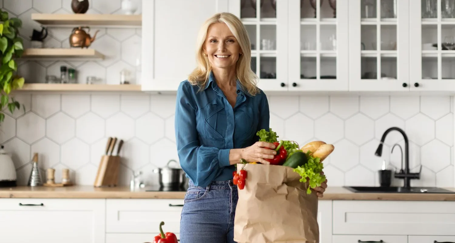 Woman unpacking fresh organic vegetables from a grocery bag in her kitchen