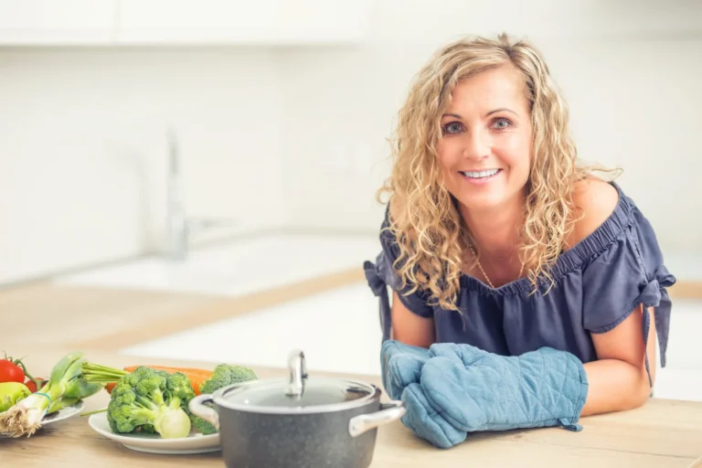 Woman over 40 preparing vegetables in kitchen representing healthy, balanced nutrition