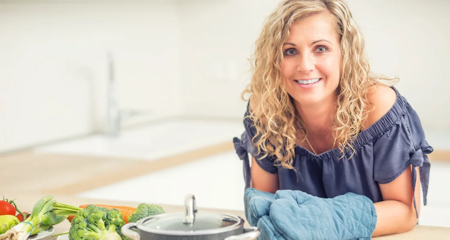 Woman over 40 preparing vegetables in kitchen representing healthy, balanced nutrition
