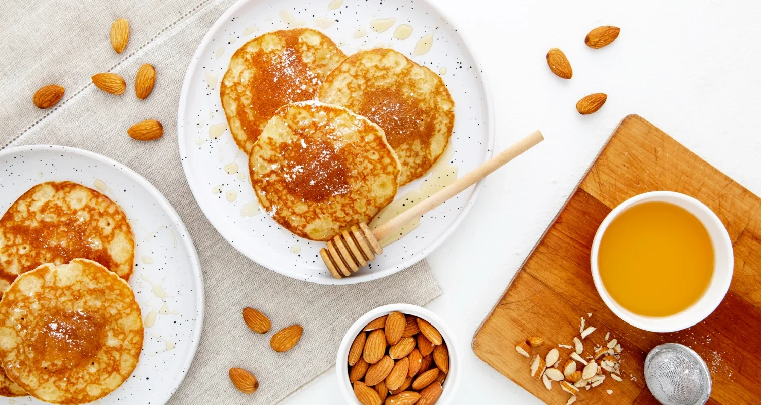 Stack of almond flour protein pancakes with fresh berries on a white plate